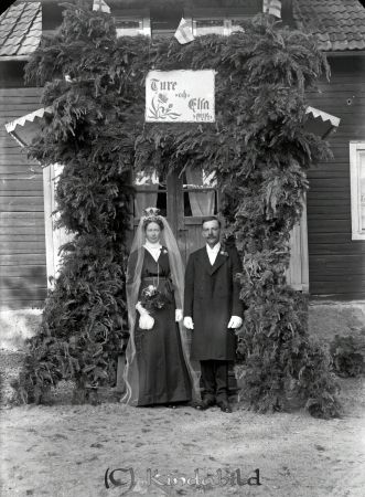 Ture Karlsson Krågedal Tjärstad
godj
Beställningstext: Ture Karlsson, Krågedal, Tjärstad 
Porträtt med brudpar under äreport framför verandan
Datum: 1914-06-24
Nyckelord: Karlsson Krågedal