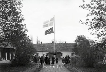 Grupporträtt med elva personer på gården framför hus med flaggning
godj
Grupporträtt med elva personer på gården framför hus med flaggning
Nyckelord: Grupporträtt