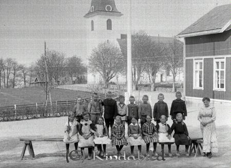 Skolklass med sexton elever och en lärarinna i NorraVi
godj
Skolklass med sexton elever (åtta pojkar och åtta flickor) och en lärarinna på en bänk framför Kyrkskolan och Kyrkan i Norra Vi
Nyckelord: Skolklass Norra Vi