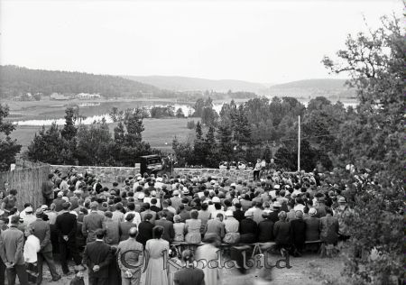 Allsångskväll på bygdegården sommaren 1955.
raja
En samling människor framför en sångare och en man som spelar piano på platsen där idag kaffestugan ligger på Hembygdsgården i Kisa. I bakgrunden Värgårdsudde och Kisasjön.  

Nyckelord: Allsångskväll bygdegården