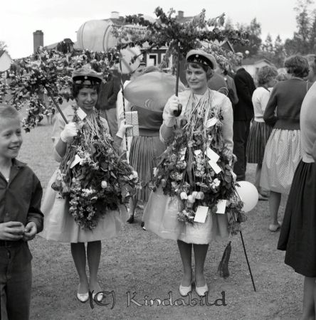 Realexamen Kisa Skola
raja
Två kvinnliga studenter med blommor och ballonger runt sina halsar. Håller också i var sitt stativ till paraply klädda med blommor. 

Nyckelord: Skola Kisa