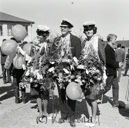 Realexamen 1963 A-klass
raja
Två kvinnliga och en manlig student med blommor och ballonger runt sina halsar
Nyckelord: Realexamen Kisa