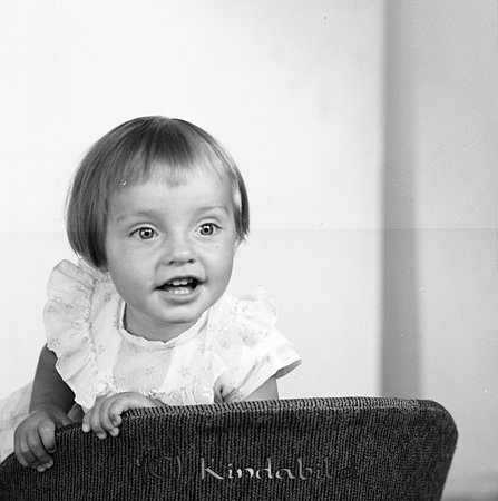 Annika och Carina Wiktorsson Kisa
gepe
En liten flicka i 3-4 årsådern klädd i klänning med volang, står på lnä bakvänt i en stol.
Nyckelord: Wiktorsson Kisa
